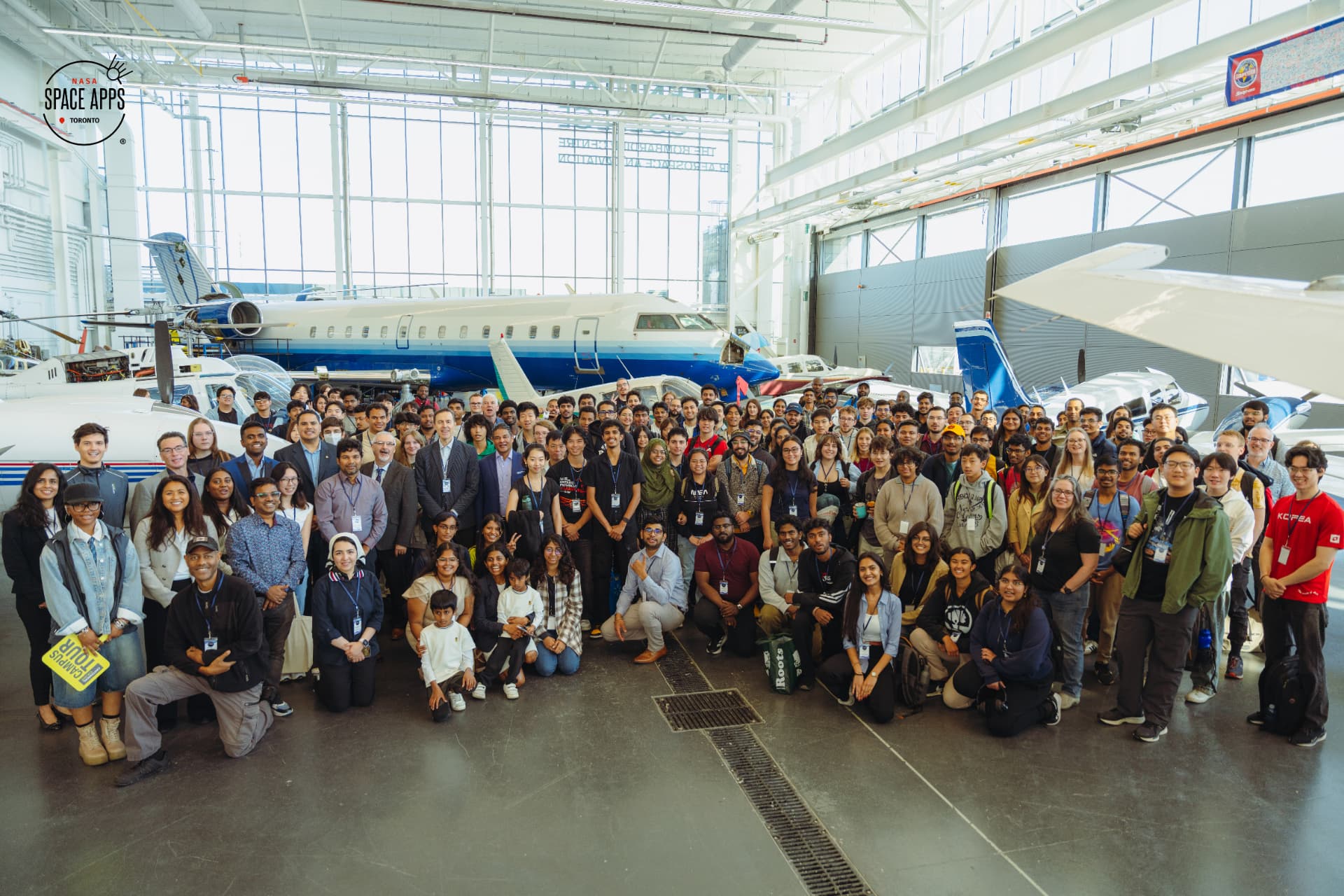 NASA Space Apps Toronto 2025 participants, mentors and organizers gathered inside the hangar at the Bombardier Centre for Aerospace and Aviation